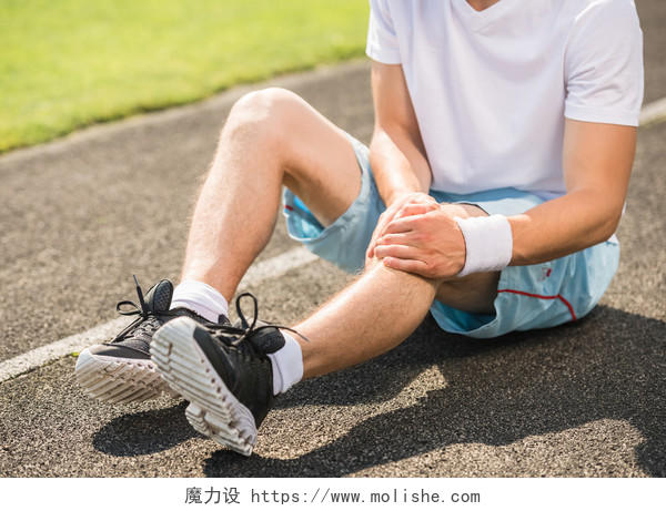 灰色赛道上男运动员触摸踝关节扭伤的脚运动健身户外跑步
